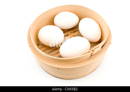 Quatre oeufs blancs dans panier de bambou isolated on white Banque D'Images