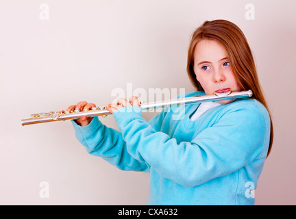 Jeune fille aux cheveux longs et haut bleu jouant d'une flûte Banque D'Images