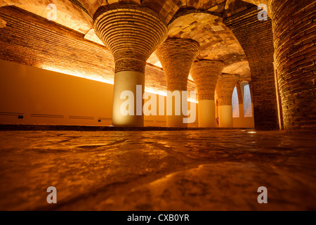 Rangée de colonnes de briques rondes anciennes illuminées dorées et d'arches dans le bâtiment de soutien du sous-sol Banque D'Images