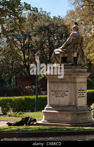 Un tramp accueille sous la statue de Pietro Paleopapa dans le Giardini Papadopoli (jardins Papadopoli) près de Piazzale Roma, Venise, Italie Banque D'Images