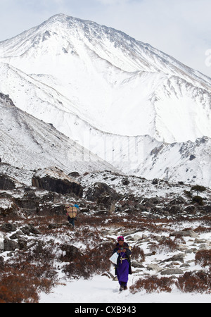 Tamang femme vêtue de vêtements traditionnels à marcher le long d'un sentier dans la neige le long de la vallée du Langtang, au Népal Banque D'Images