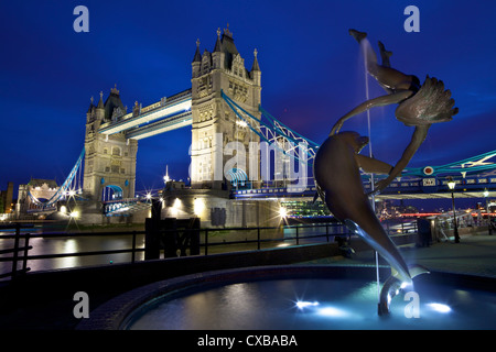 Fille avec un dauphin, statue de David Wynne, illuminé la nuit devant le Tower Bridge, Londres, Angleterre, Royaume-Uni Banque D'Images