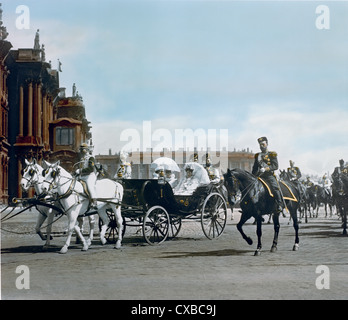 Photo colorisée du tsar russe Nicholas II (1868 - 1918) à côté d'une calèche transportant son épouse, la russe Tsarina Alexandra Feodorovna d'origine allemande, également connue sous le nom d'Alix de Hesse, (1872 - 1918) mère, l'impératrice danoise Maria Feodorovna (1847 - 1928) et sœur, la Grande Duga russe d'échecs Olrovna (1882 - 1960) défilé du Palais d'hiver, Saint-Pétersbourg, Russie, 1901. Le cortège impérial se déplace vers un examen des troupes. (Photo de Burton Holmes) Banque D'Images