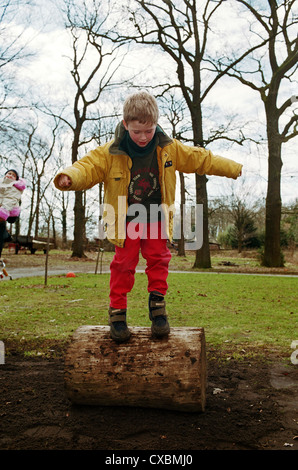 Garçon en équilibre sur une souche d'arbre dans le jardin, le nord de l'Allemagne Banque D'Images