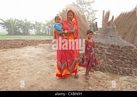 Mère en sari rouge et ses deux enfants en milieu rural à l'aube, village de Bihari Sonepur, Bihar, Inde, Asie Banque D'Images