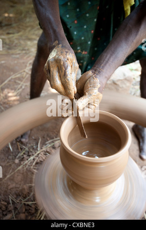 Mains de village en utilisant l'outil pour former potter pot en argile sur la roue tournante dans son village, près de l'atelier de Mirbel, Orissa, Inde Banque D'Images