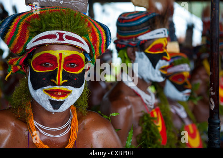 Habillés de couleurs vives et le visage peint les tribus locales pour célébrer la traditionnelle chanter chanter dans les hautes terres de Papouasie Nouvelle Guinée Banque D'Images