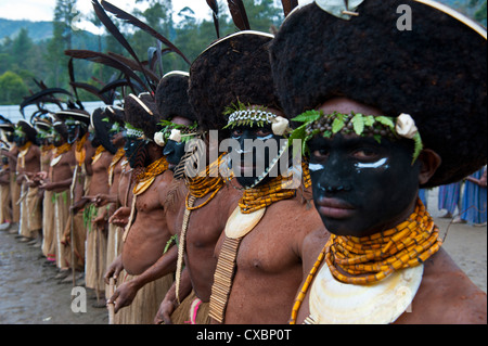 Habillés de couleurs vives et le visage peint les tribus locales pour célébrer la traditionnelle chanter chanter dans les hautes terres de Papouasie Nouvelle Guinée Banque D'Images