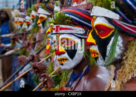 Habillés de couleurs vives et le visage peint les tribus locales pour célébrer la traditionnelle chanter chanter dans les hautes terres de Papouasie Nouvelle Guinée Banque D'Images