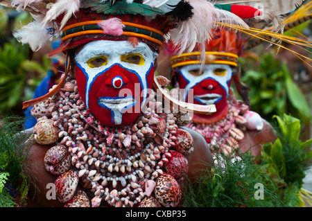 Habillés de couleurs vives et le visage peint les tribus locales pour célébrer la traditionnelle chanter chanter, Enga, hautes terres de Papouasie Nouvelle Guinée Banque D'Images