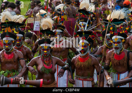 Habillés de couleurs vives et le visage peint les tribus locales pour célébrer la traditionnelle chanter chanter dans les hautes terres de Papouasie Nouvelle Guinée Banque D'Images