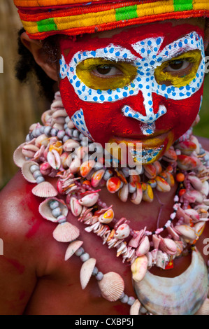 Habillés de couleurs vives et le visage peint enfant locaux traditionnels célébrant le chanter chanter dans les hautes terres de Papouasie Nouvelle Guinée Banque D'Images