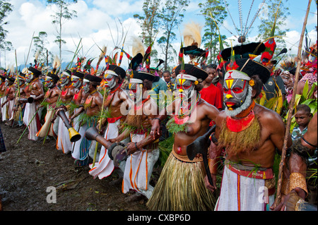 Habillés de couleurs vives et le visage peint les tribus locales pour célébrer la traditionnelle chanter chanter dans les hautes terres de Papouasie Nouvelle Guinée Banque D'Images