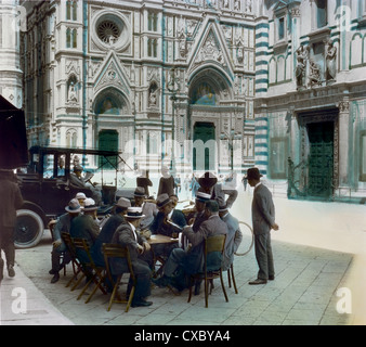 Photo colorisée d'hommes conversant à une table près de la cathédrale de Florence sur la Piazza del Duomo, Florence, Italie, 1924. (Photo de Burton Holmes) Banque D'Images