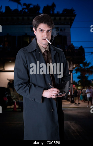 L'acteur John Scamardella dépeint un homme sérieux dans un trench coat, dans les rues de Key West. Banque D'Images
