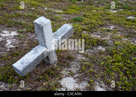 Enterré Croix. Une pierre tombale en forme de croix partiellement dans les sables mouvants de l'Hopetown cimetière. Banque D'Images