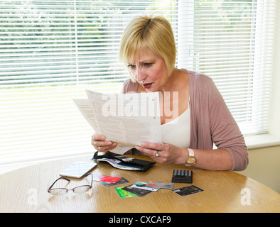 Femme choqué à la lecture de sa facture de carte de crédit Banque D'Images