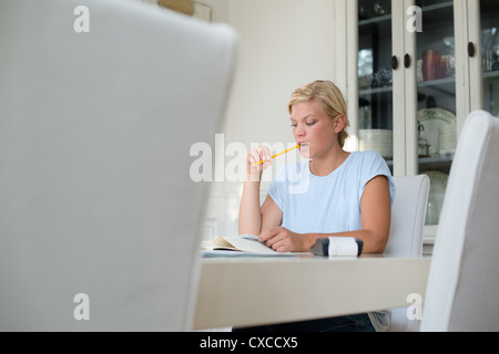 Jeune femme blonde cette vérification et l'utilisation de calculatrice à la maison Banque D'Images