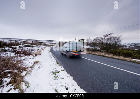 Blurred motion de Toyota Land Cruiser 4x4 voyager passé champs blancs le long de la lande route sur le froid, la neige d'hiver - West Yorkshire, Angleterre, Royaume-Uni. Banque D'Images