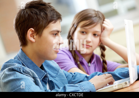 Portrait of teenage girl looking at tapant guy at lesson Banque D'Images