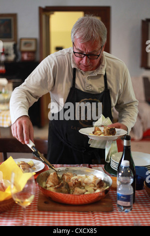 Un Italien du Nord à la maison servant de la cuisine traditionnelle (stockfish avec l'oignon et les pommes de terre). Friuli Venezia Giulia, Italie. Banque D'Images