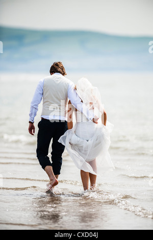 Un couple nouvellement marié à la pagaie mer après leur mariage sur un après-midi d'été, Ynyslas beach, Ceredigion Pays de Galles UK Banque D'Images