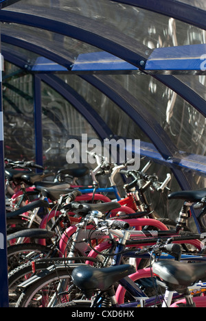 Les vélos garés infiltration en toute sécurité dans une aire de stationnement à l'extérieur d'une gare d'Angleterre. Banque D'Images