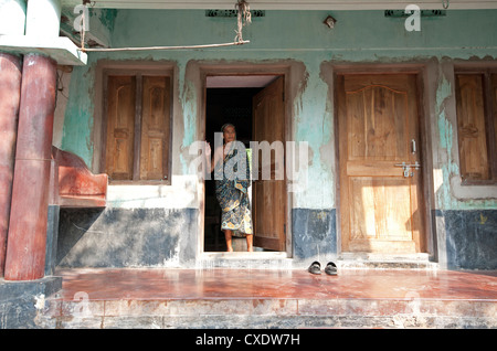 Femme en sari à vieille maison de bois porte dans Raghurajpur village des artistes, de l'Orissa, Inde, Asie Banque D'Images