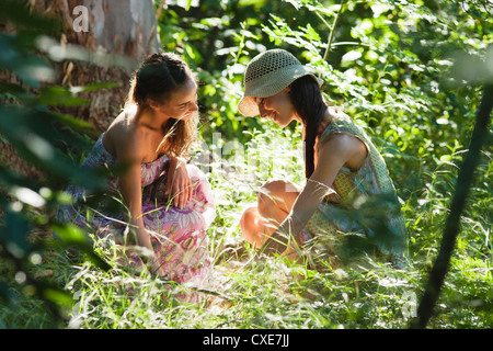 Les jeunes femmes crouching in woods, face à face Banque D'Images