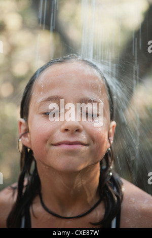 Fille sous l'eau courante à l'extérieur Banque D'Images