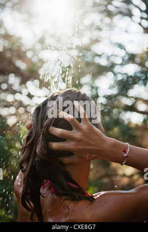 Girl le lavage des cheveux à l'eau courante à l'extérieur, vue arrière Banque D'Images