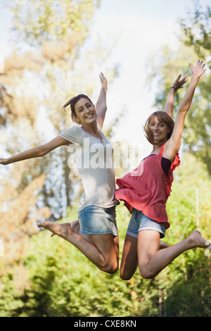 Les jeunes femmes sautant dans l'air, smiling Banque D'Images