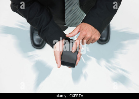 Businessman standing on world map, en utilisant smartphone, cropped Banque D'Images