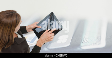 Woman using digital tablet, image d'étui contenant les cartes de crédit en surimpression sur l'arrière-plan Banque D'Images