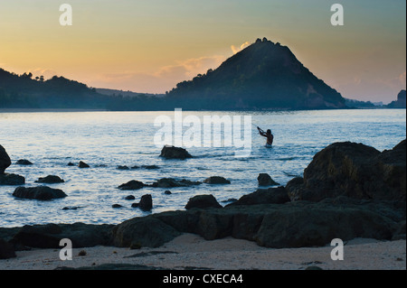 L'homme de la pêche au filet au lever du soleil sur la plage de Kuta, Lombok, Indonésie, Asie du Sud, Asie Banque D'Images