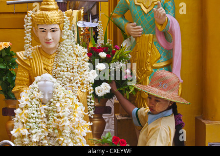 Une statue de Bouddha recouverte de fleurs à la PAYA SHWEDAGON PAGODA ou qui date de 1485 - Yangon, Myanmar Banque D'Images