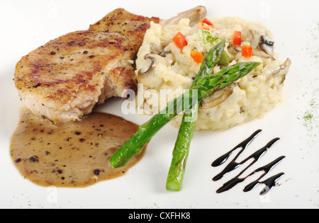 Risotto aux asperges vertes, et de la viande avec la sauce sur une assiette blanche garnie (Selective Focus) Banque D'Images