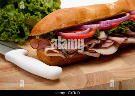 Sandwich sous-marin sur une planche à découper, un couteau et laitue Banque D'Images