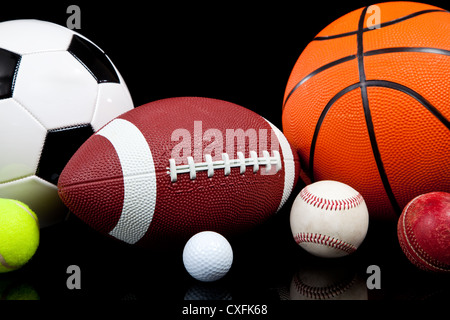 Un assortiment de ballons de sport sur un fond noir Banque D'Images