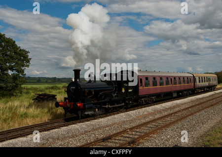 Une vieille locomotive à vapeur crée les nuages qui se confondent avec le ciel bleu et nuages comme elle voyage à travers la campagne. Banque D'Images