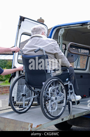 Un homme âgé en fauteuil roulant sur la rampe d'une plate-forme de levage spécialisée véhicule adapté pour le transport des personnes à mobilité réduite service volontaire Banque D'Images