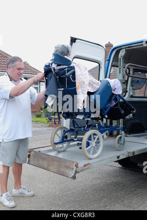 Vieille Femme dans un fauteuil roulant sur la rampe d'une plate-forme de levage spécialisée véhicule adapté pour le transport des personnes à mobilité réduite service volontaire Banque D'Images