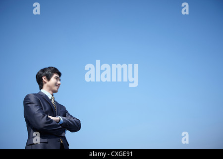 Un businessman standing with arms crossed Banque D'Images