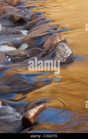 Un coucher du soleil doré reflétée dans une petite cascade sur la rivière Breamish dans le Northumberland, UK Banque D'Images