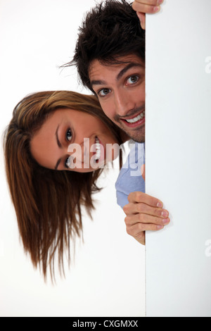Jeune femme et l'homme se cacher derrière la porte Banque D'Images