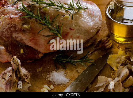 Epaule d'agneau piqué à l'ail, frotté avec du sel et l'huile d'olive, garni de romarin parfumé prêt pour le four. Banque D'Images