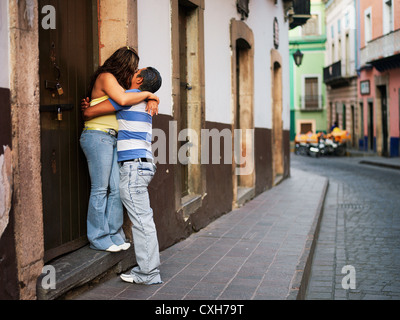 Un jeune couple intimement baiser, tenir la main, et s'embrassent sur une petite rue. Aucune autorisation Modèle disponible Banque D'Images