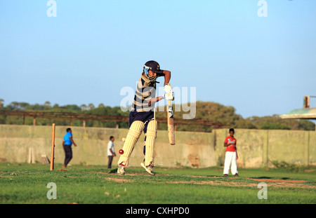 Les jeunes hommes jouant un jeu de cricket pratique à Trincomalee, Sri Lanka. Banque D'Images