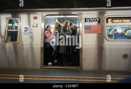 Les passagers s'entassent dans un panier-E train dans le métro de New York dans les quartiers de Queens Banque D'Images