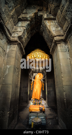 Bouddha saint habillé en orange dans archway à Angkor Wat temple complexe à Siem Reap, Cambodge Banque D'Images